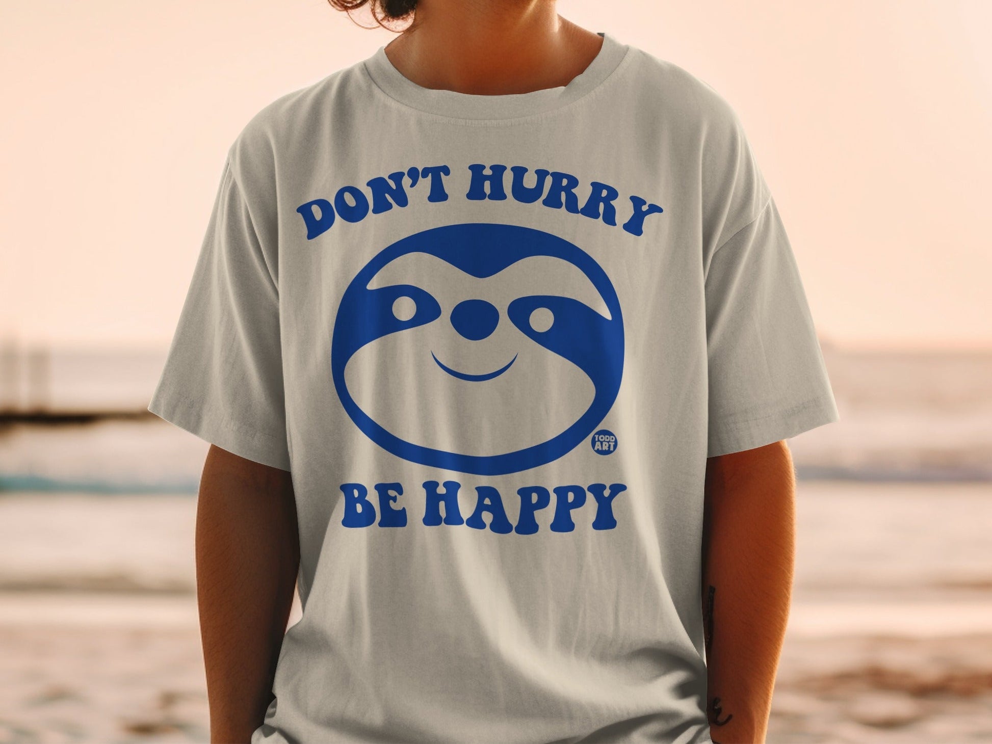 Gray t-shirt with blue sloth graphic and text "DON'T HURRY BE HAPPY."