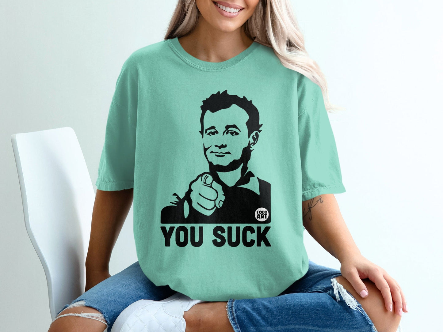 Mint t-shirt with black graphic of a man pointing and text "YOU SUCK".