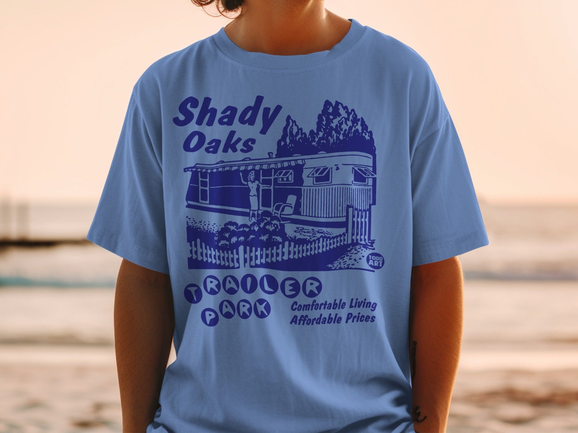 Blue t-shirt with "Shady Oaks Trailer Park" text and illustration.