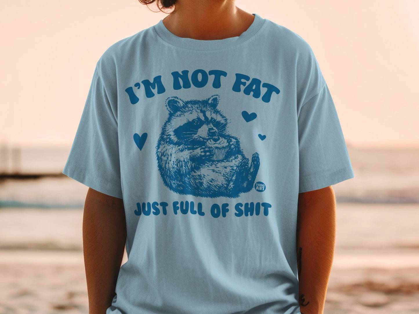 Light blue t-shirt with a raccoon and the text "I'M NOT FAT JUST FULL OF SHIT".
