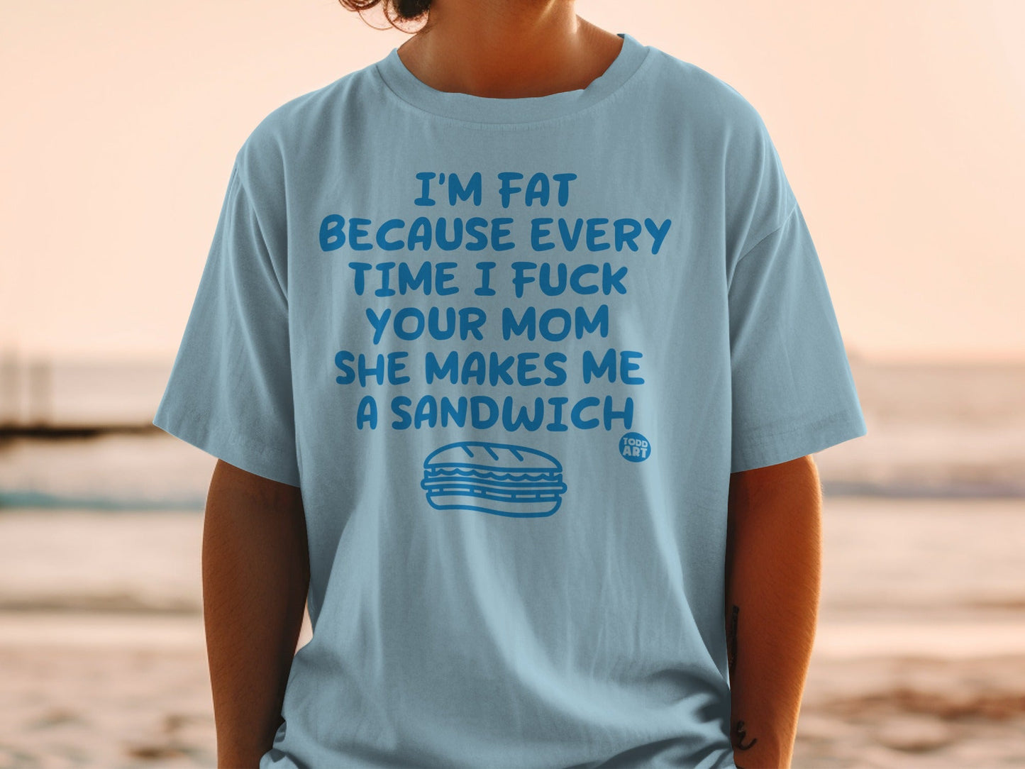 Light blue t-shirt with text "I'M FAT BECAUSE EVERY TIME I FUCK YOUR MOM SHE MAKES ME A SANDWICH" and sandwich graphic.