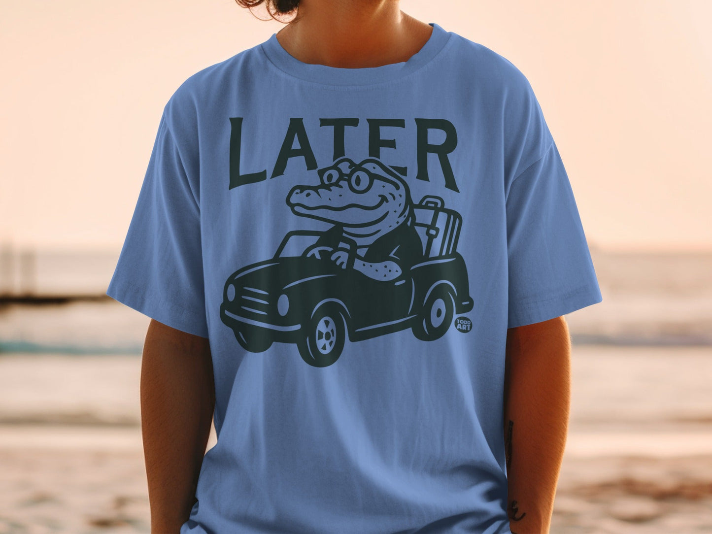 T-shirt with cartoon alligator driving a car with luggage, "LATER" text.