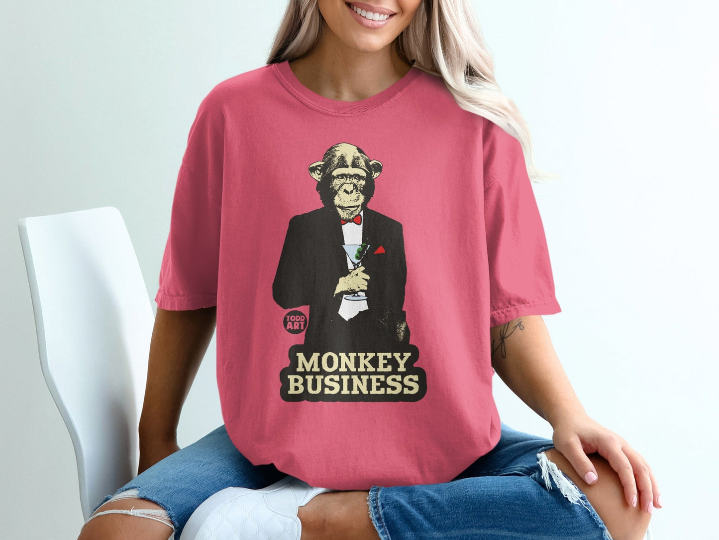 Pink t-shirt with a monkey in a tuxedo holding a martini, text "MONKEY BUSINESS".