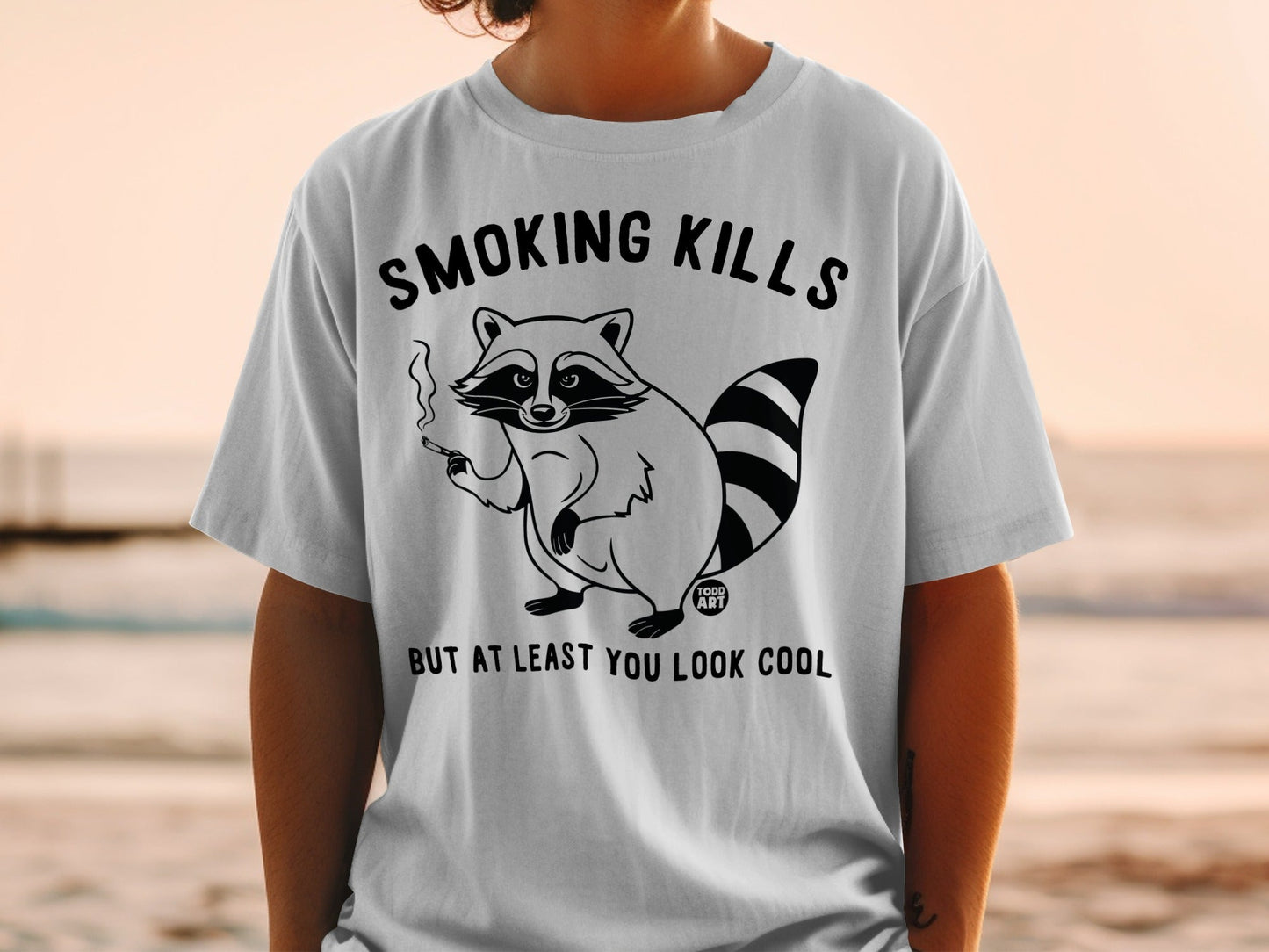 T-shirt with cartoon raccoon smoking and text "SMOKING KILLS BUT AT LEAST YOU LOOK COOL".