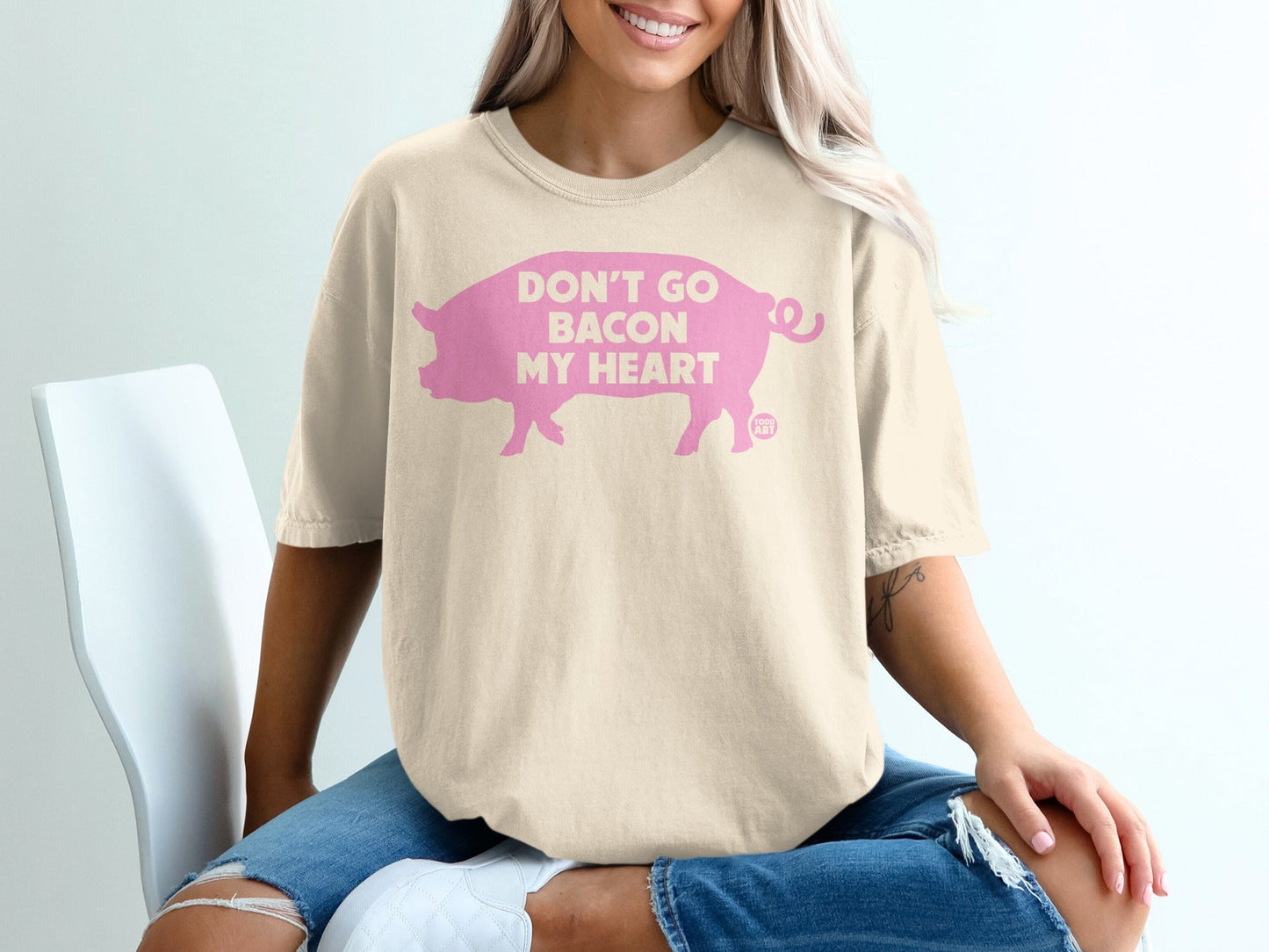 Cream t-shirt with pink pig graphic and text "DON'T GO BACON MY HEART".
