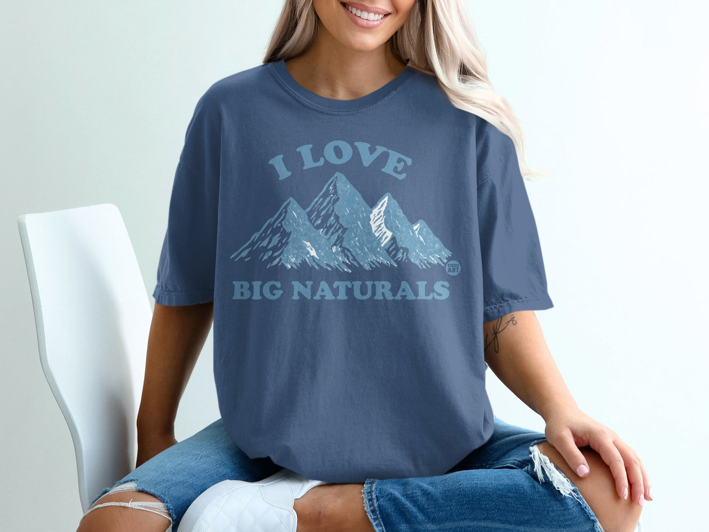 Woman in blue t-shirt with "I love BIG NATURALS" and mountains graphic.