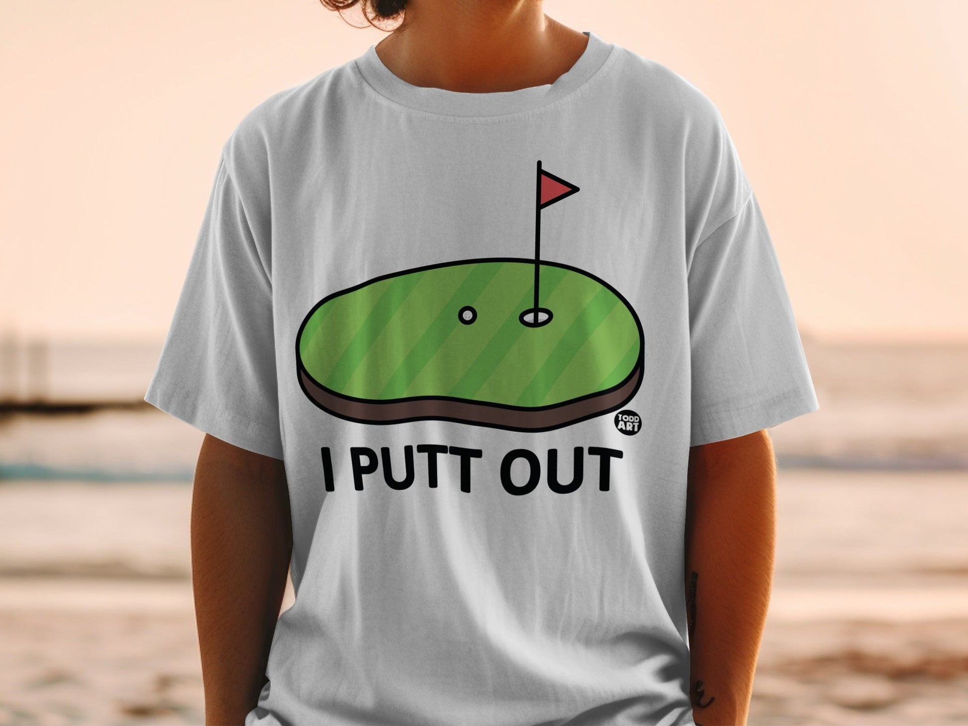 White t-shirt with "I PUTT OUT" and a golf green graphic.