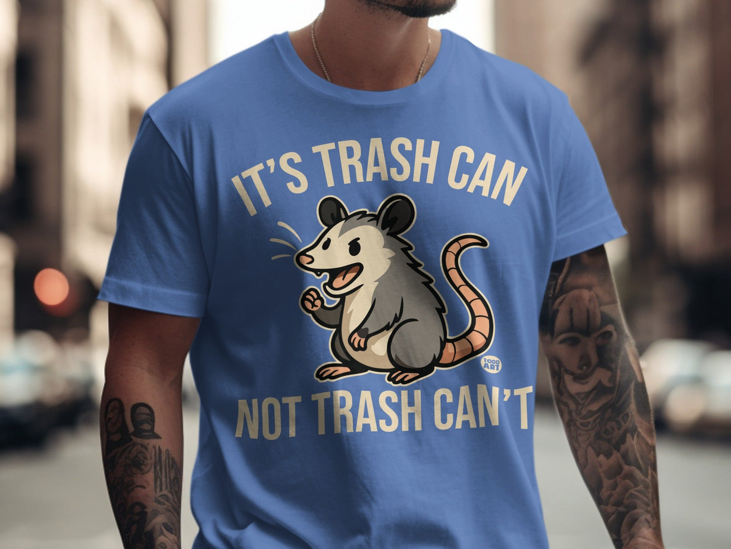 Blue t-shirt with cartoon opossum and text "IT'S TRASH CAN NOT TRASH CAN'T".