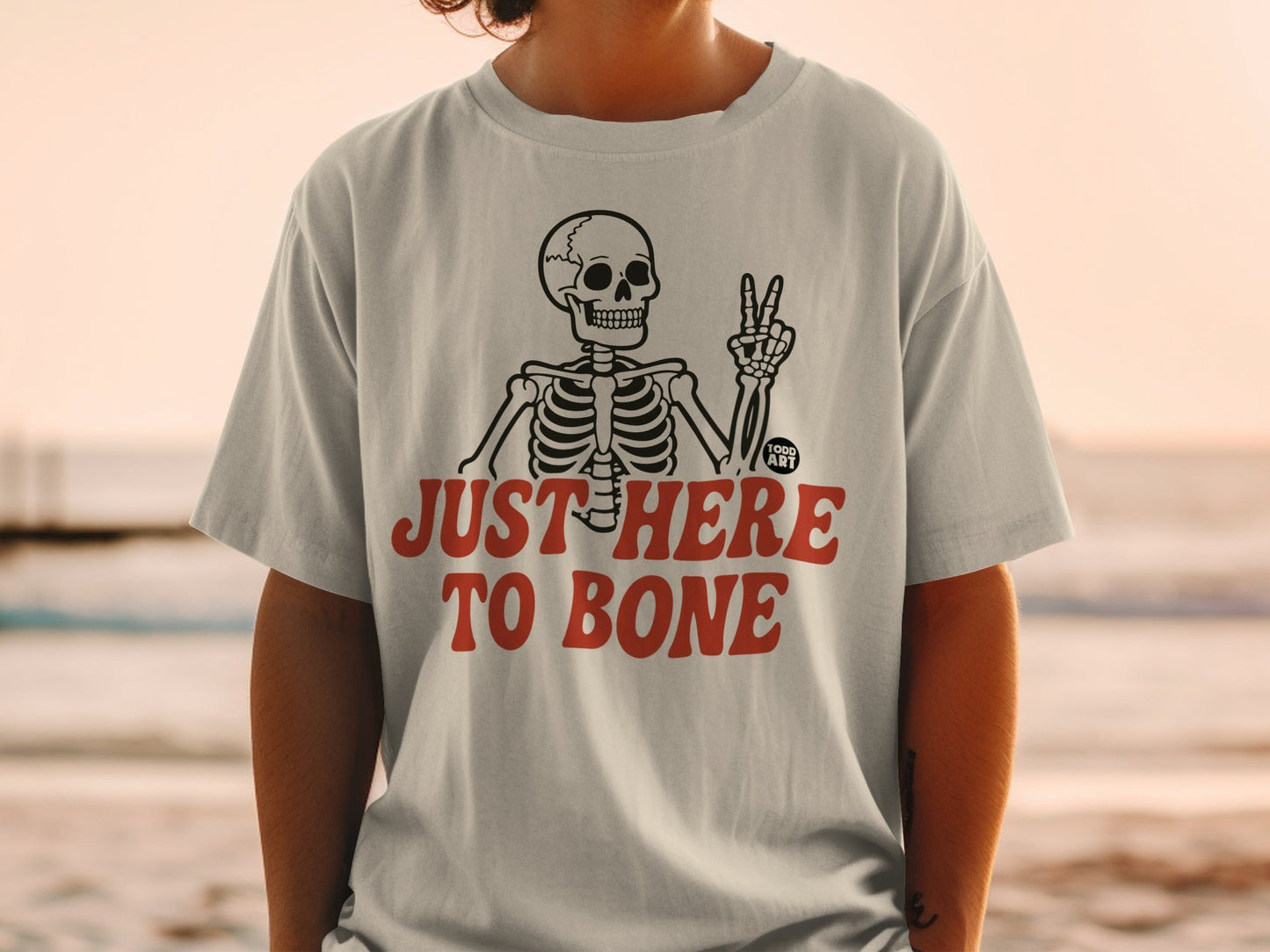 White t-shirt with "JUST HERE TO BONE" text and skeleton graphic.