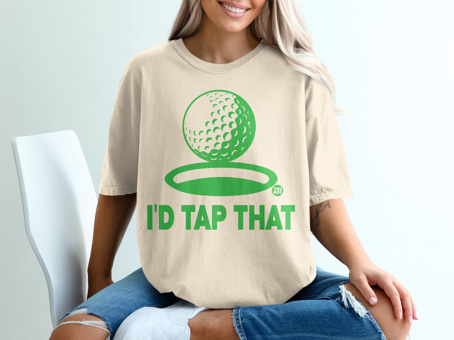 Cream t-shirt with green golf ball graphic and "I'D TAP THAT" text.