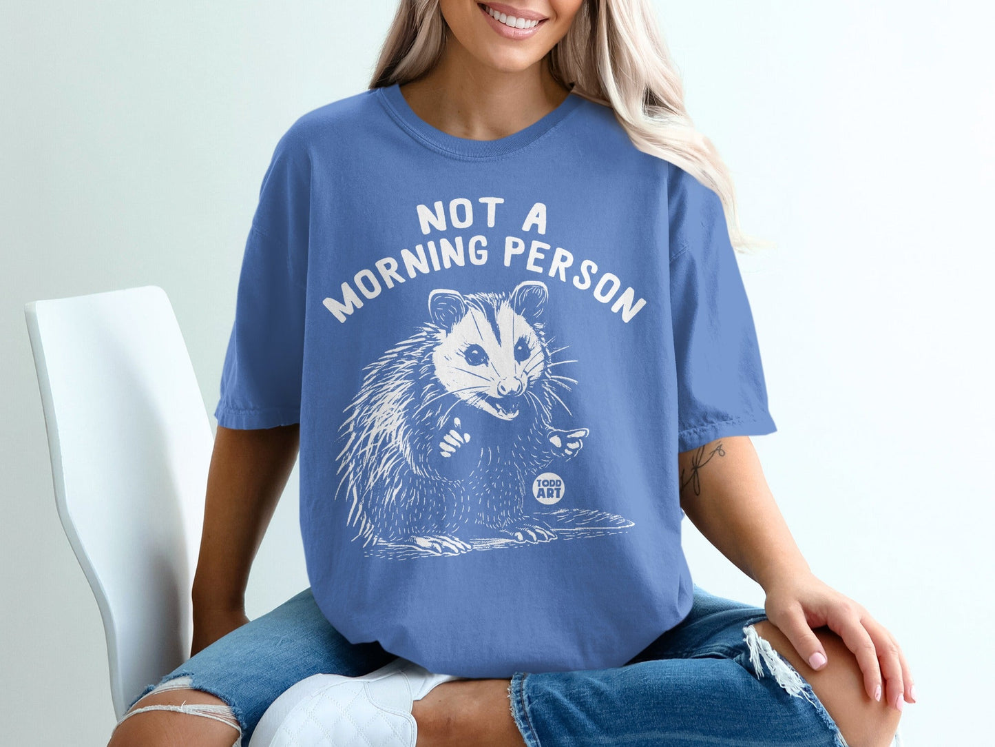 Blue t-shirt with a white drawing of a possum and text "NOT A MORNING PERSON".