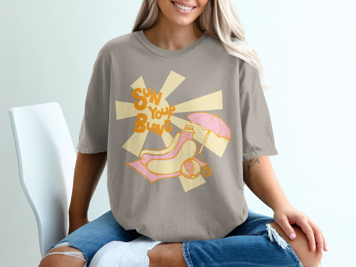 T-shirt graphic: hot dog with umbrella and sunbeams, text "SUN YOUR BUNS."