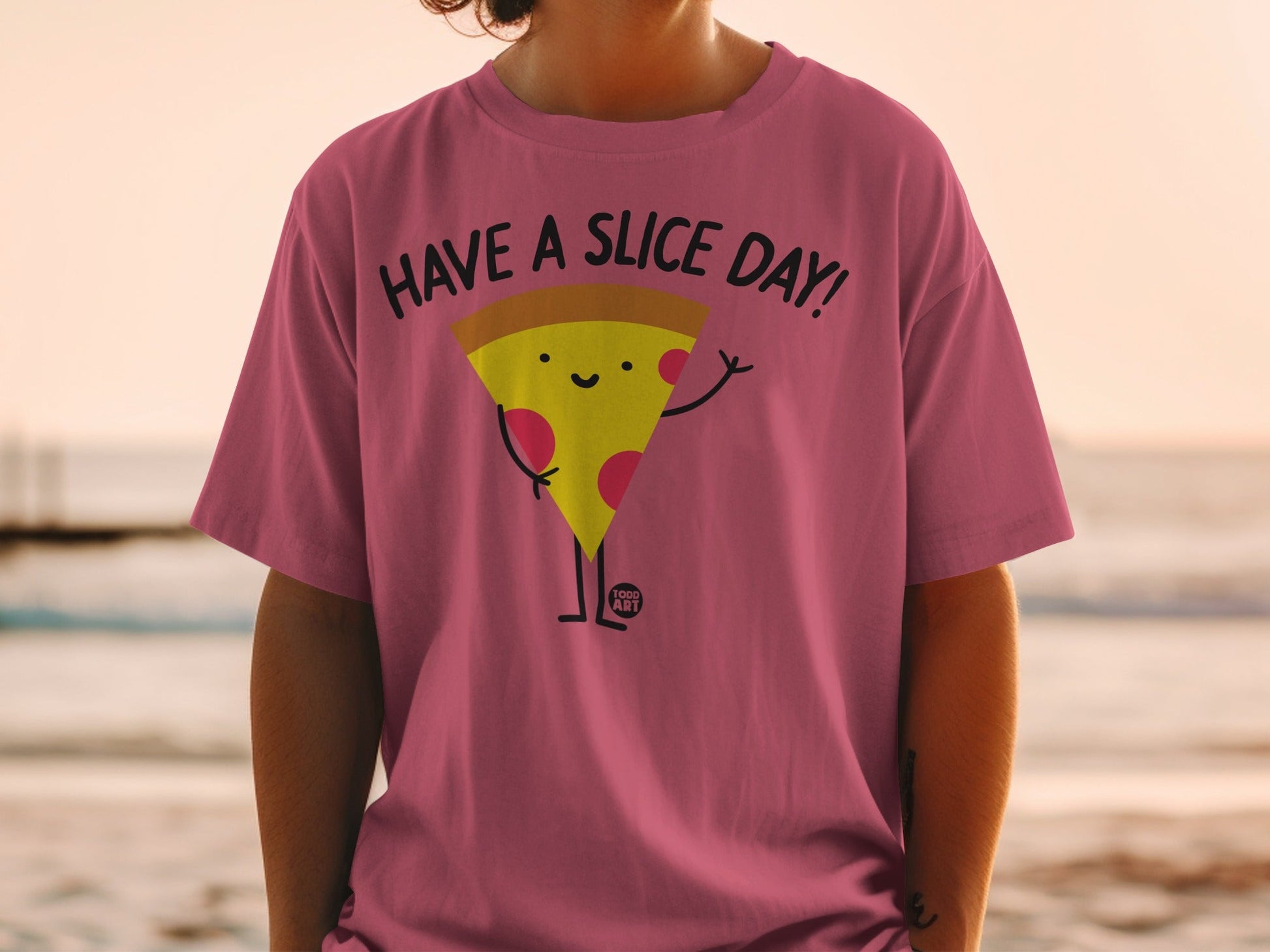 Pink t-shirt with a cartoon pizza slice saying "Have a Slice Day!"