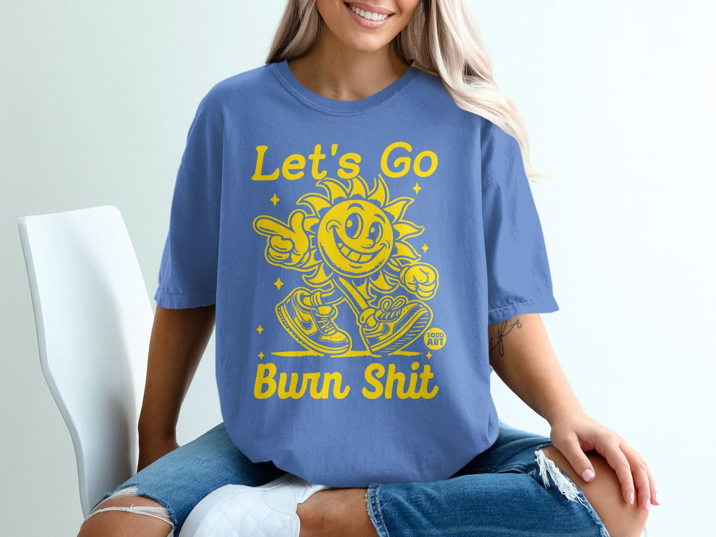 Blue t-shirt with yellow text and cartoon sun graphic.
