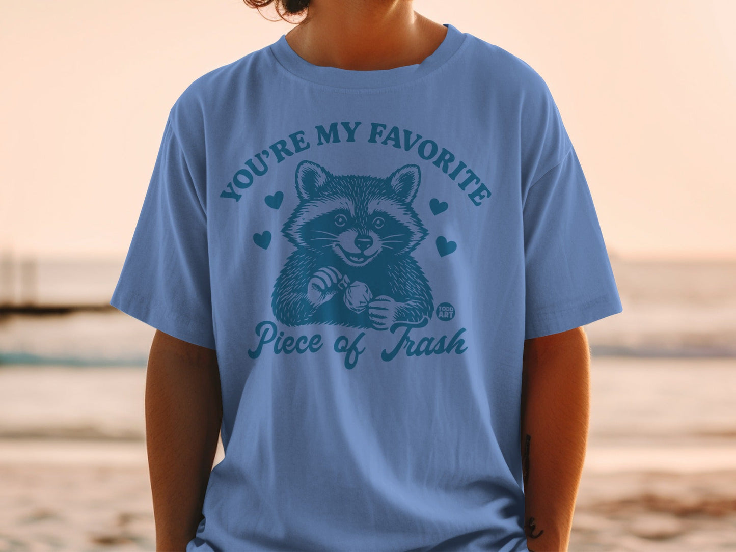 Blue t-shirt with raccoon graphic and "YOU'RE MY FAVORITE Piece of Trash" text.