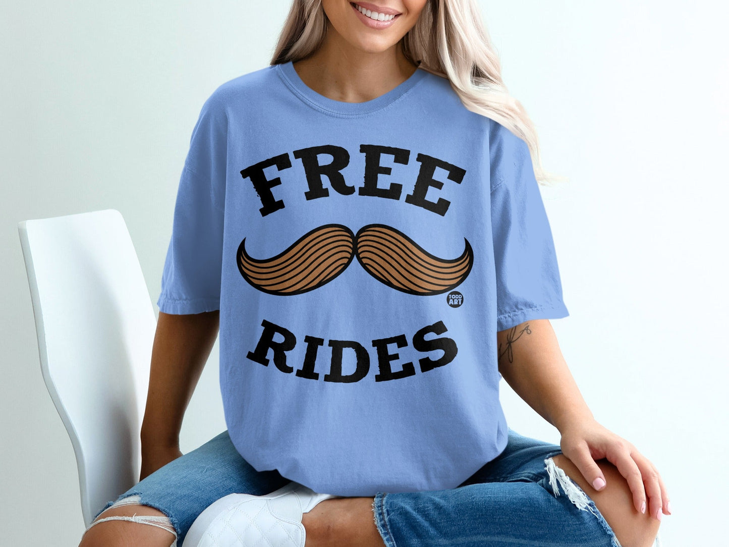 Blue t-shirt with large black text "FREE RIDES" and a brown mustache graphic.