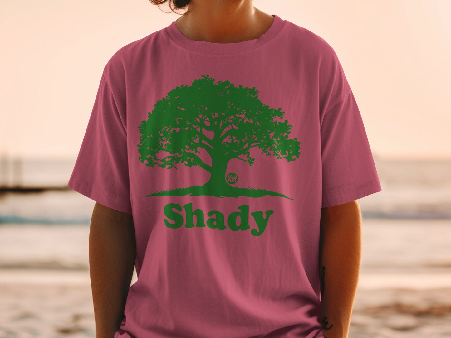 Pink t-shirt with a green tree logo and the word "Shady".