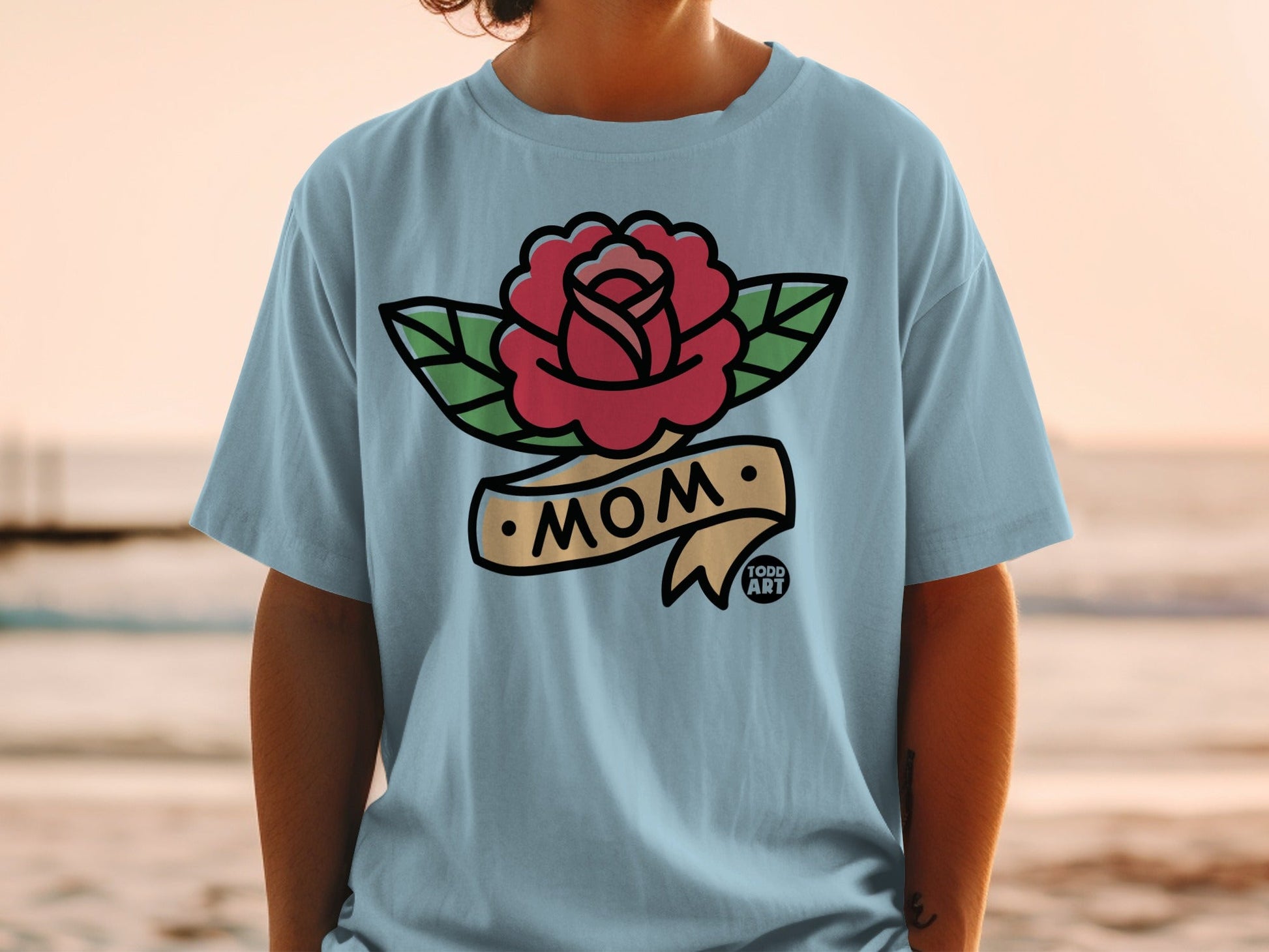 Light blue t-shirt with tattoo-style rose and "MOM" banner.