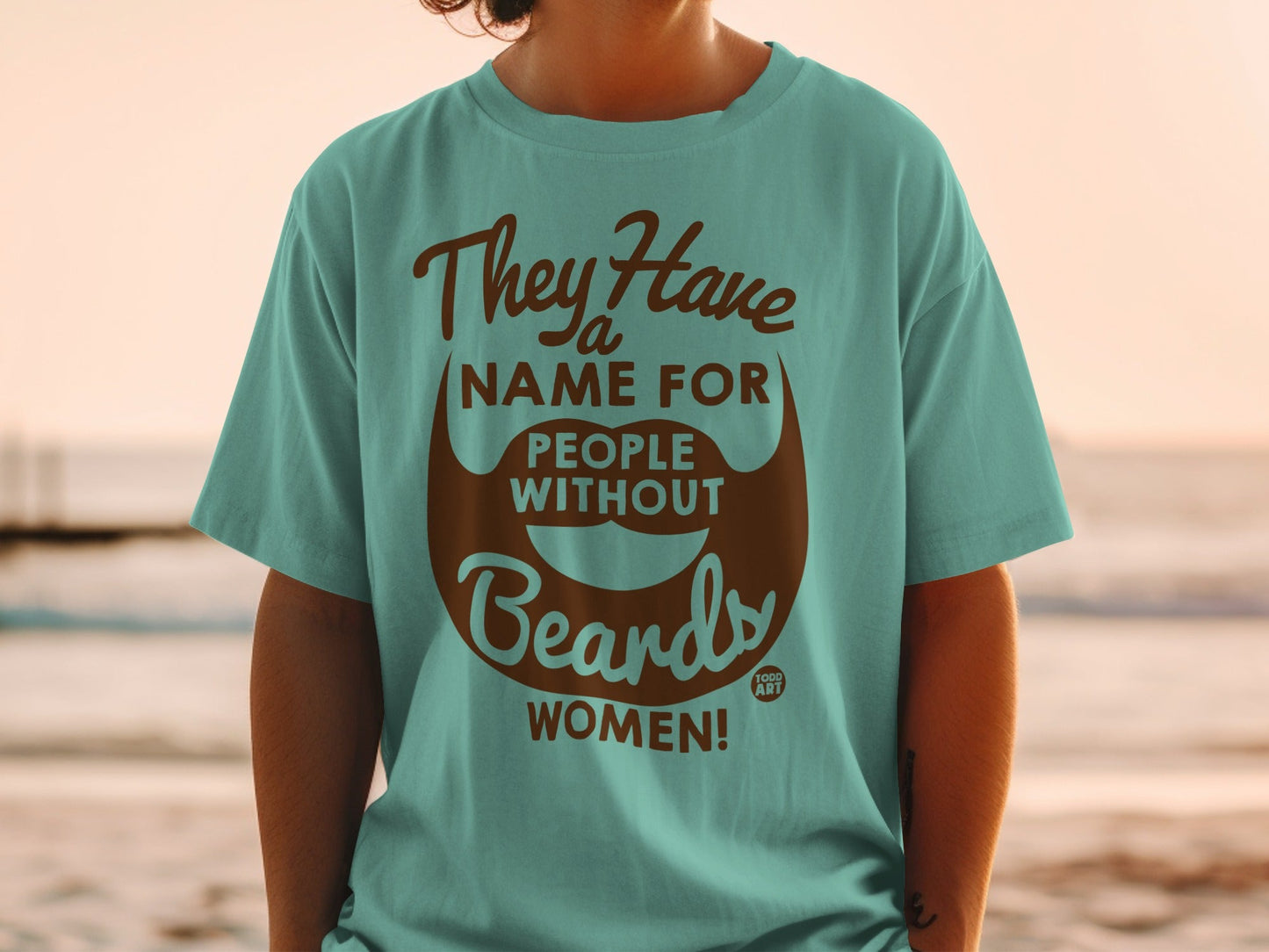 Teal t-shirt with brown text and a beard graphic saying "They Have a Name For People Without Beards: WOMEN!"