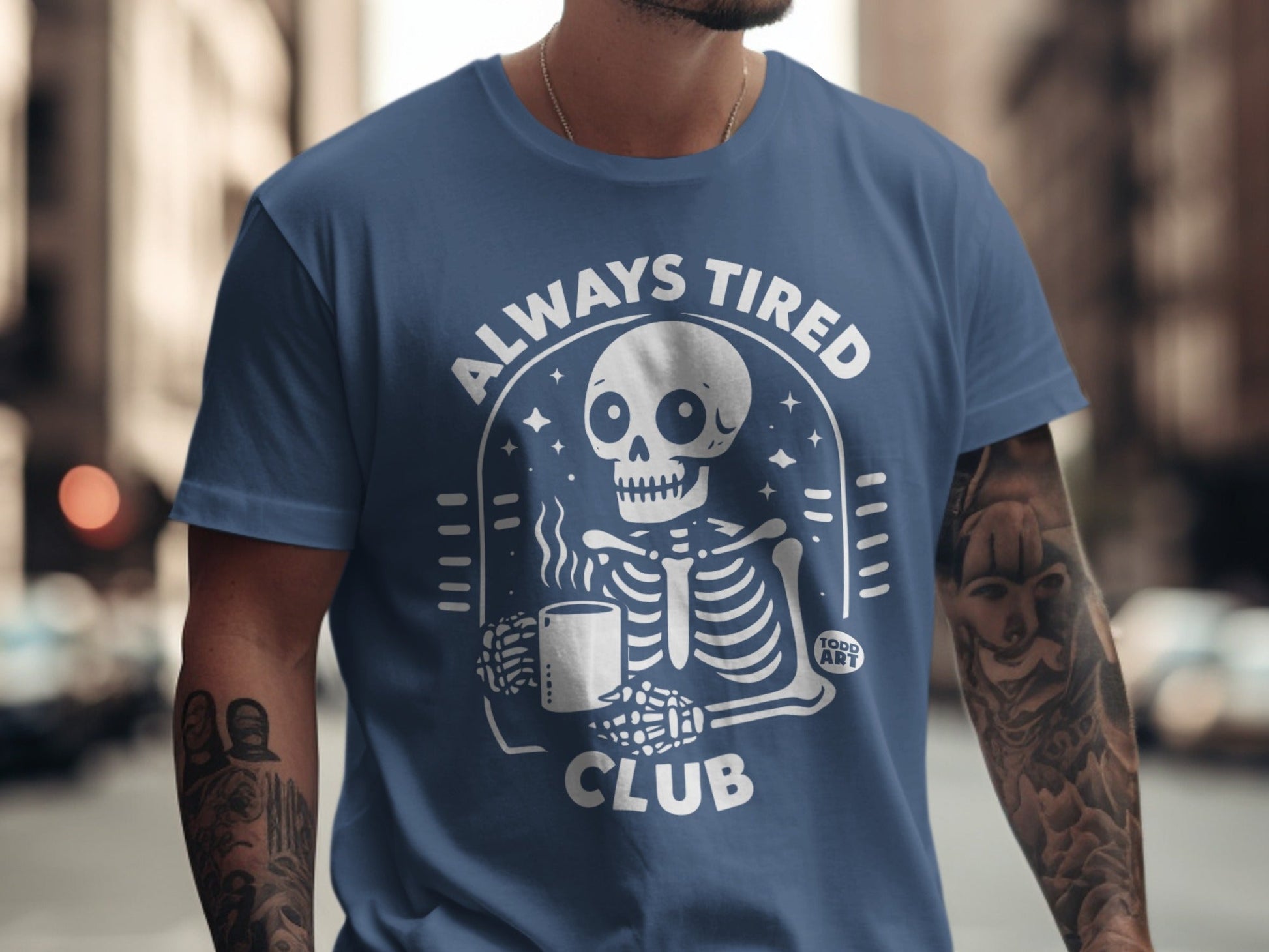 Blue t-shirt with white "Always Tired Club" text and skeleton graphic.