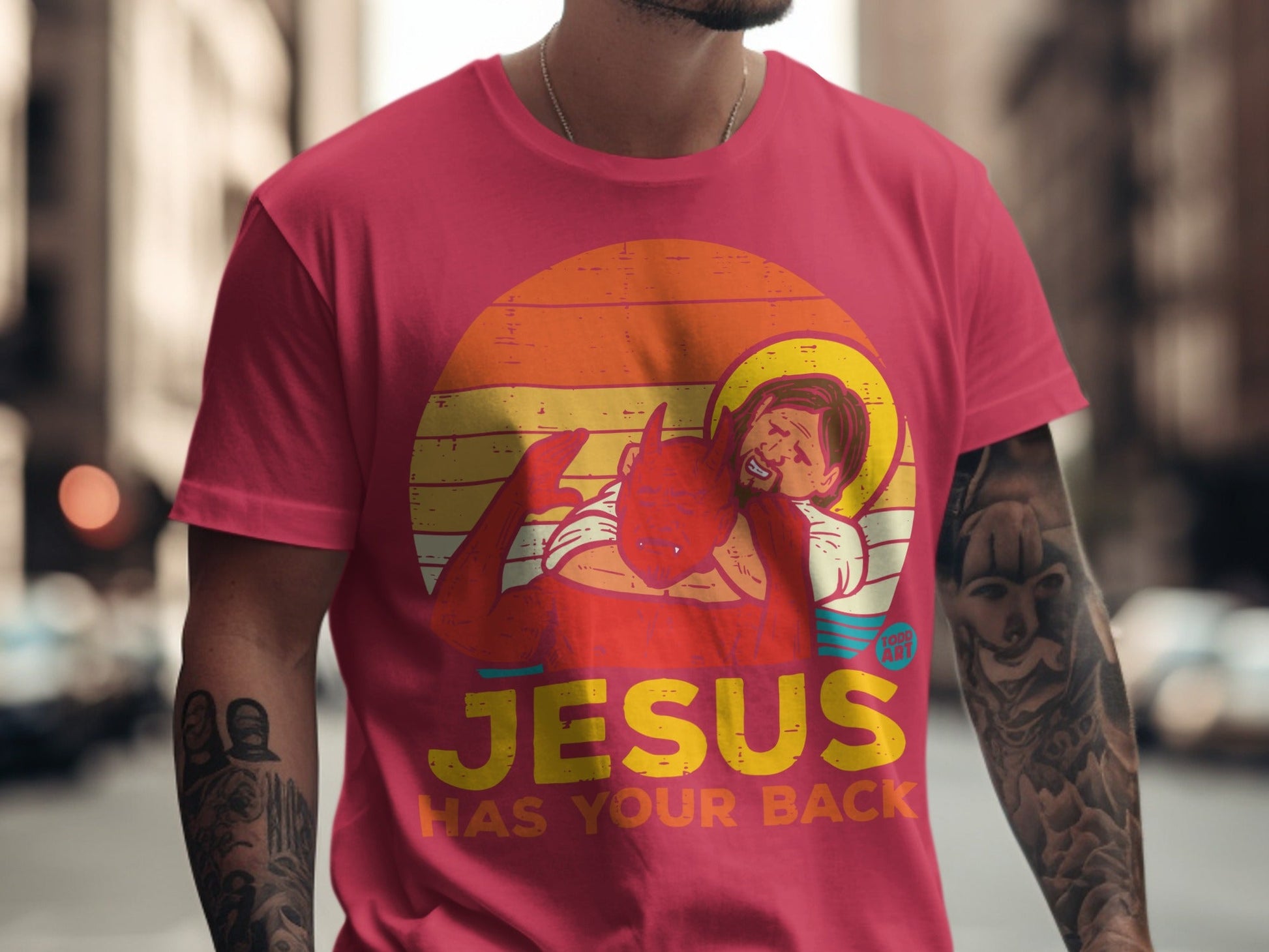 T-shirt with Jesus and devil graphic, "JESUS HAS YOUR BACK" text.