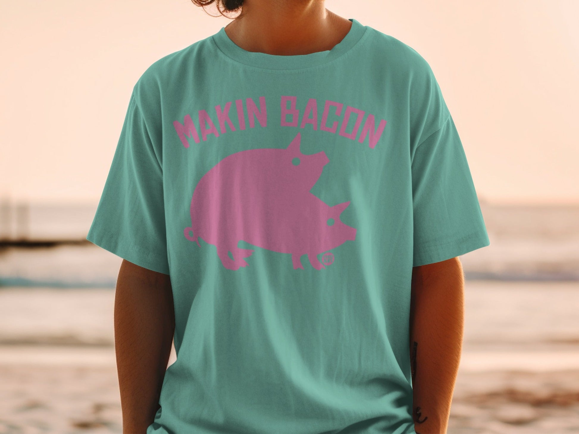 Teal t-shirt with pink text "MAKIN BACON" and graphic of two pigs.