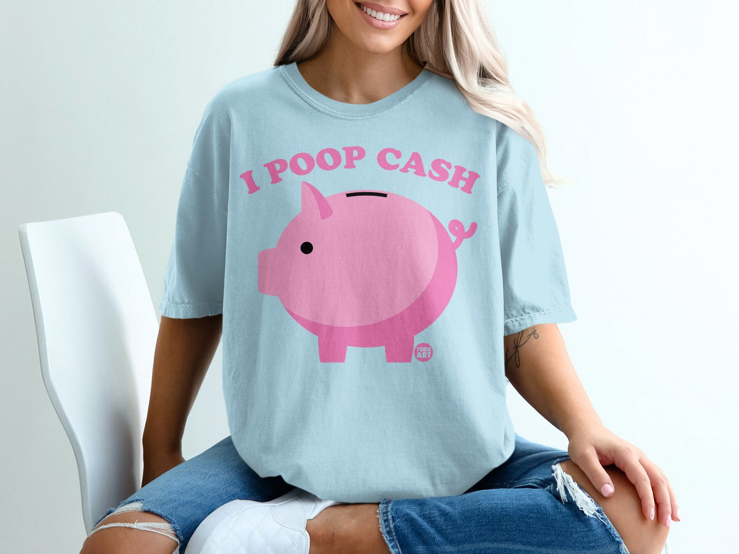 Light blue t-shirt with a pink piggy bank and "I POOP CASH" text.