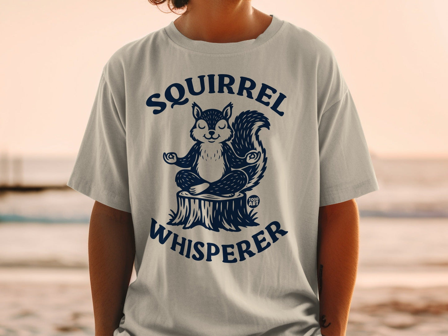 T-shirt with a meditating squirrel on a log, "Squirrel Whisperer" text.