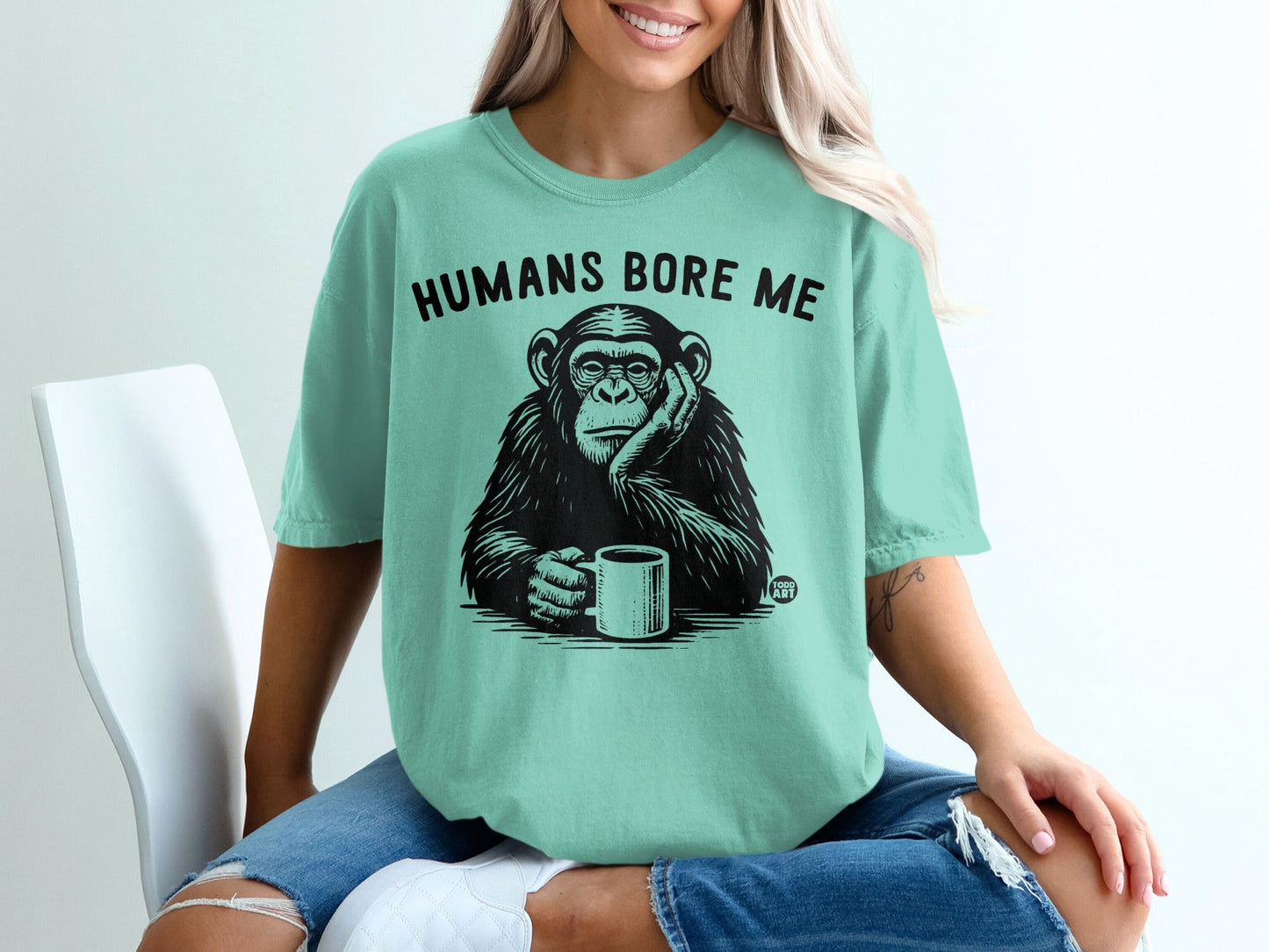 Chimpanzee holding mug, text reads "HUMANS BORE ME".
