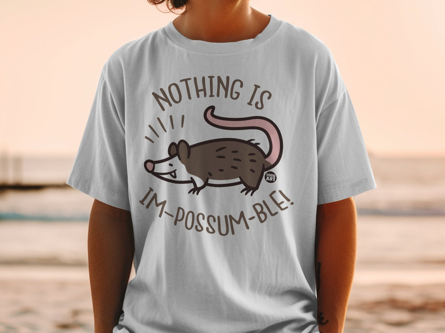 White t-shirt with a cartoon possum and text: "Nothing is im-possum-ble!".