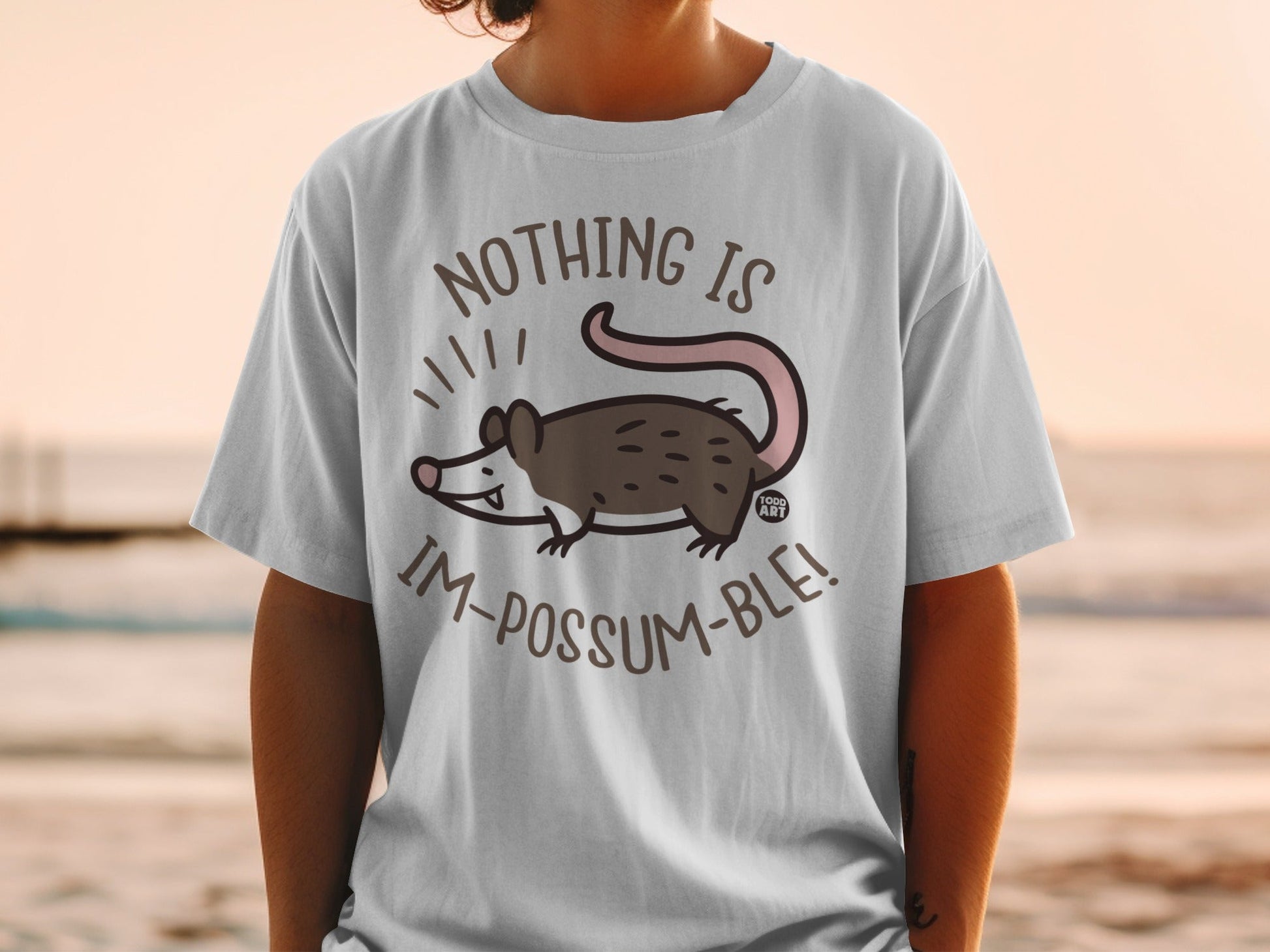 White t-shirt with a cartoon possum and text: "Nothing is im-possum-ble!".