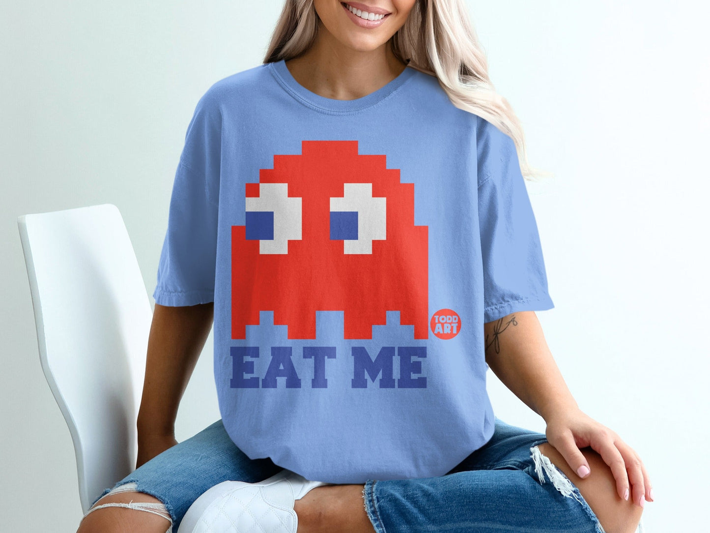 Blue t-shirt with a pixelated red ghost and "EAT ME" text.