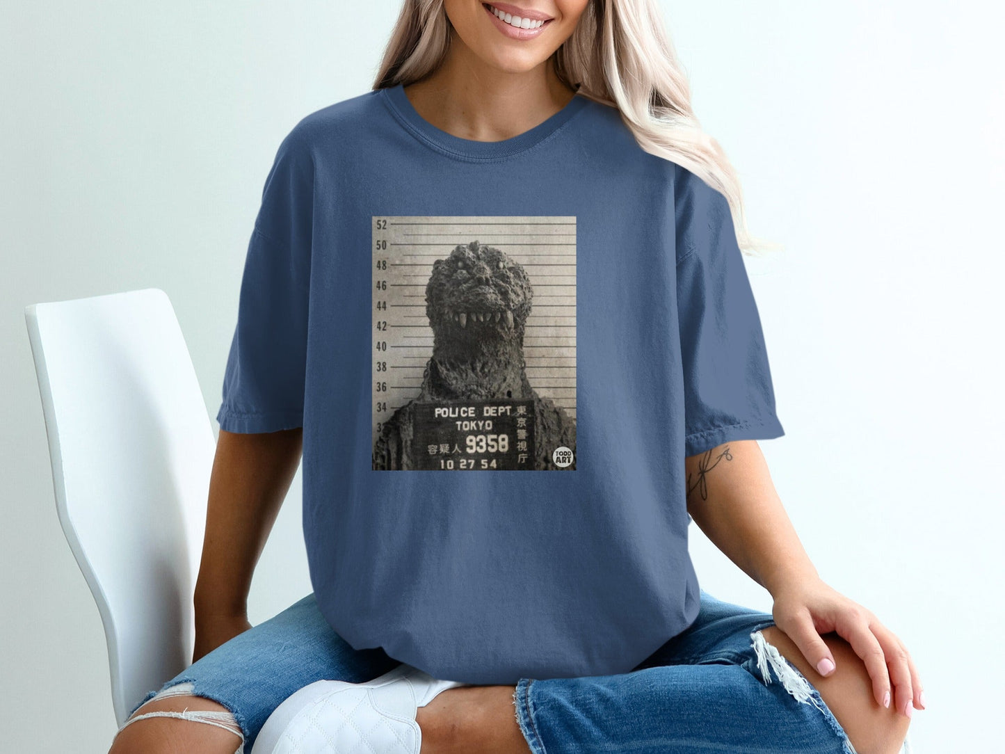 Godzilla mugshot graphic on a blue t-shirt.