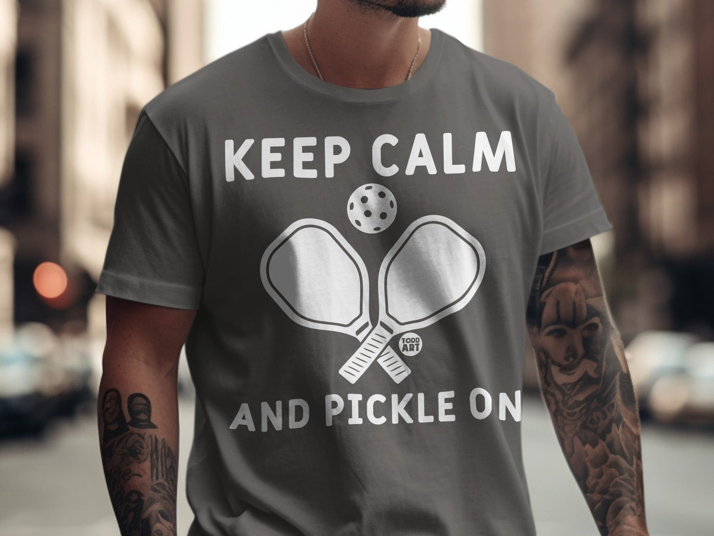 Grey t-shirt with "Keep Calm and Pickle On" text and pickleball paddles.