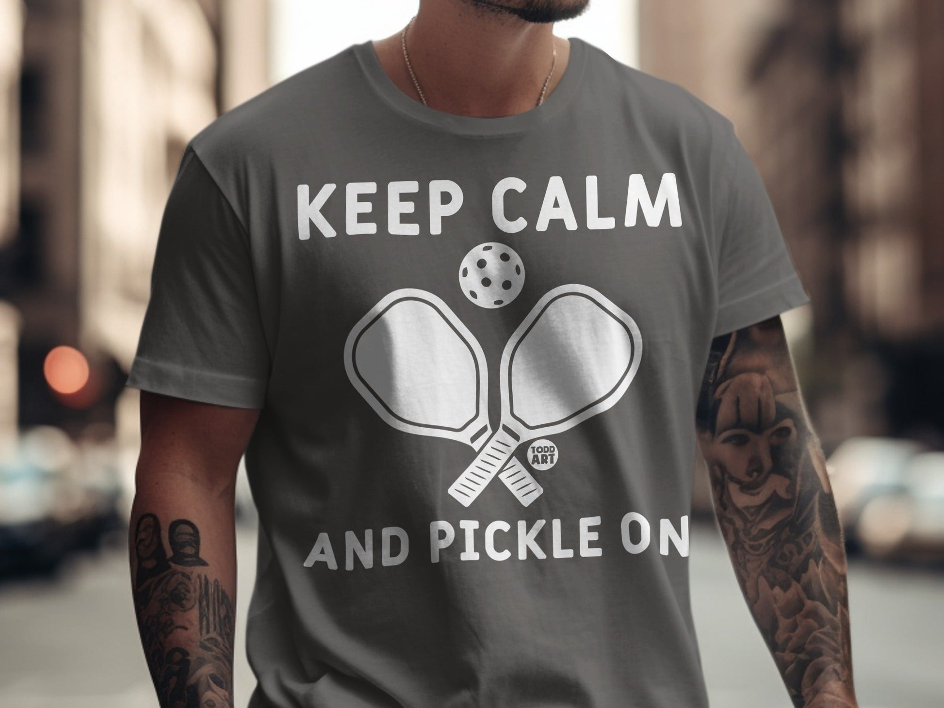 Grey t-shirt with "Keep Calm and Pickle On" text and pickleball paddles.