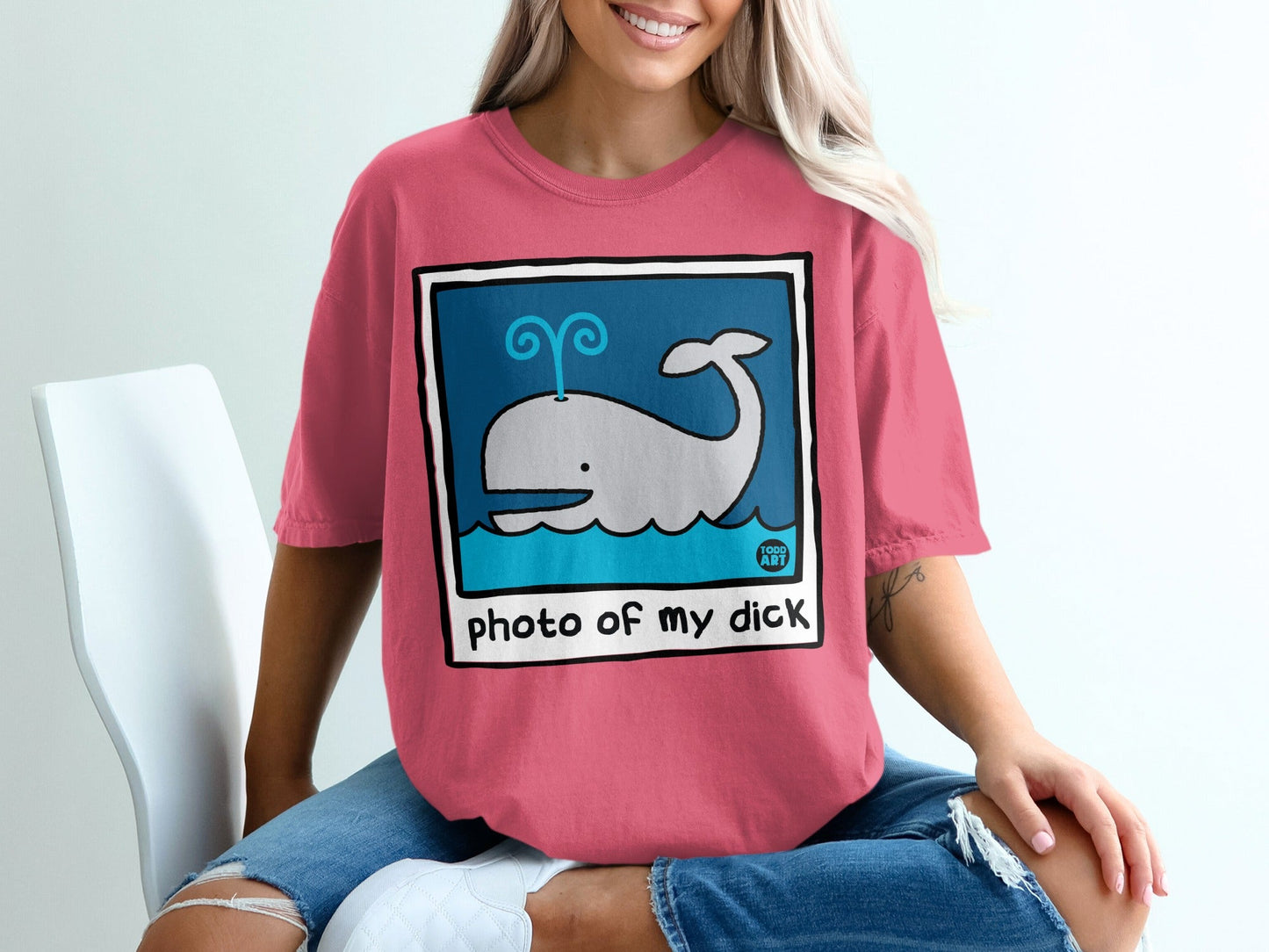Pink t-shirt with a cartoon whale spraying water and the text "photo of my dick".