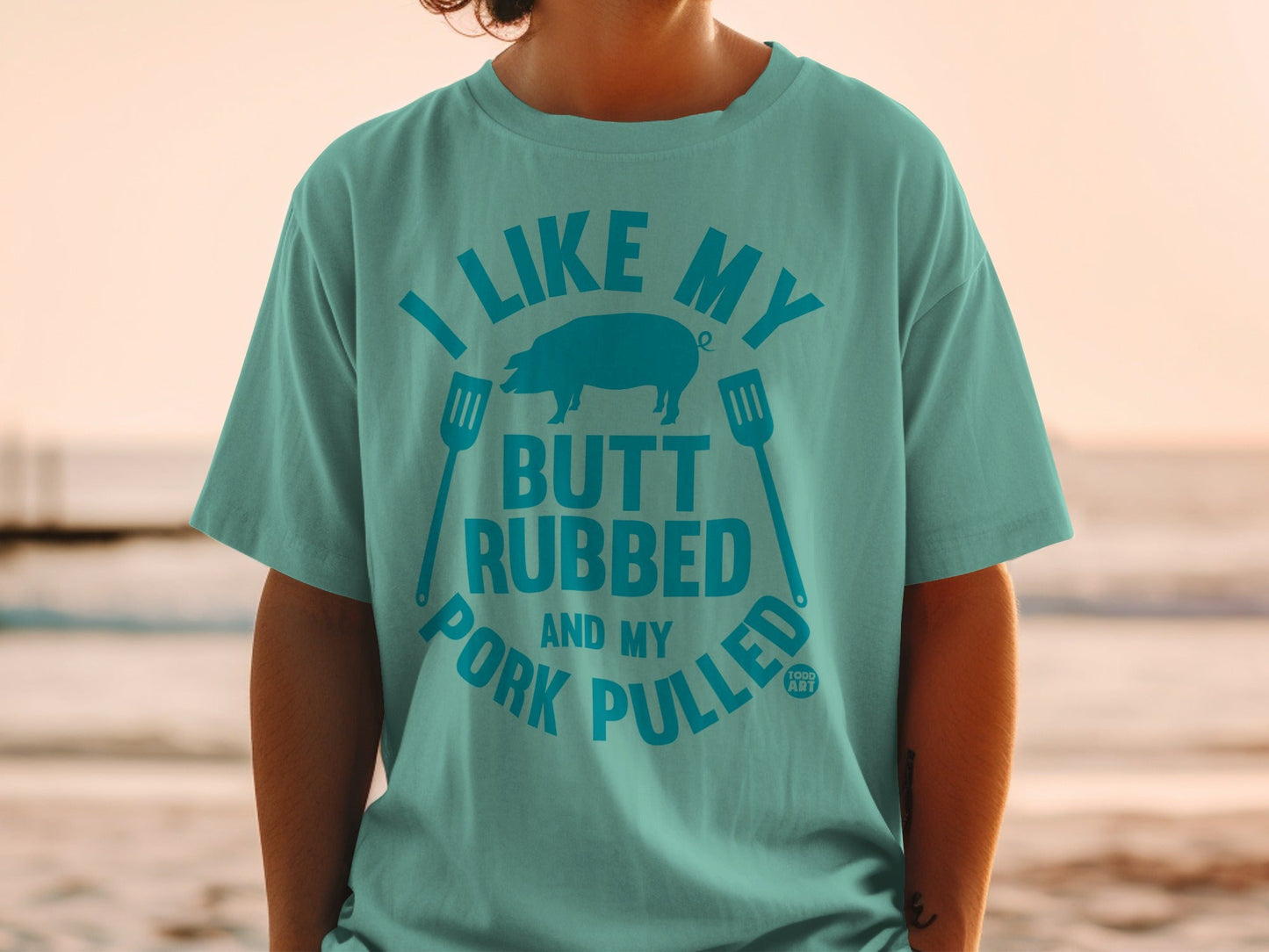 Teal t-shirt with "I Like My Butt Rubbed and Pork Pulled" graphic and pig silhouette.