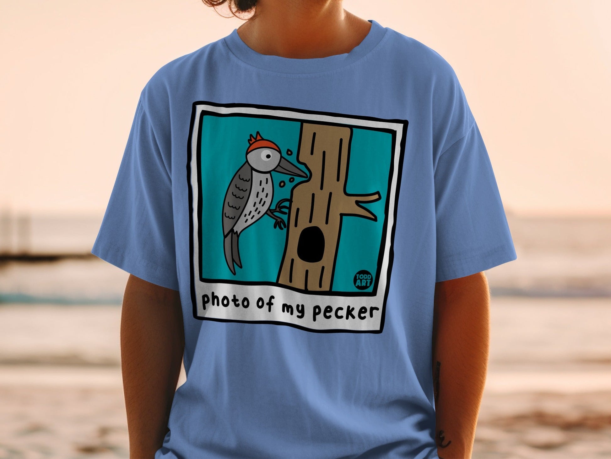 T-shirt with cartoon woodpecker on a tree, text "photo of my pecker" and "100% ART".