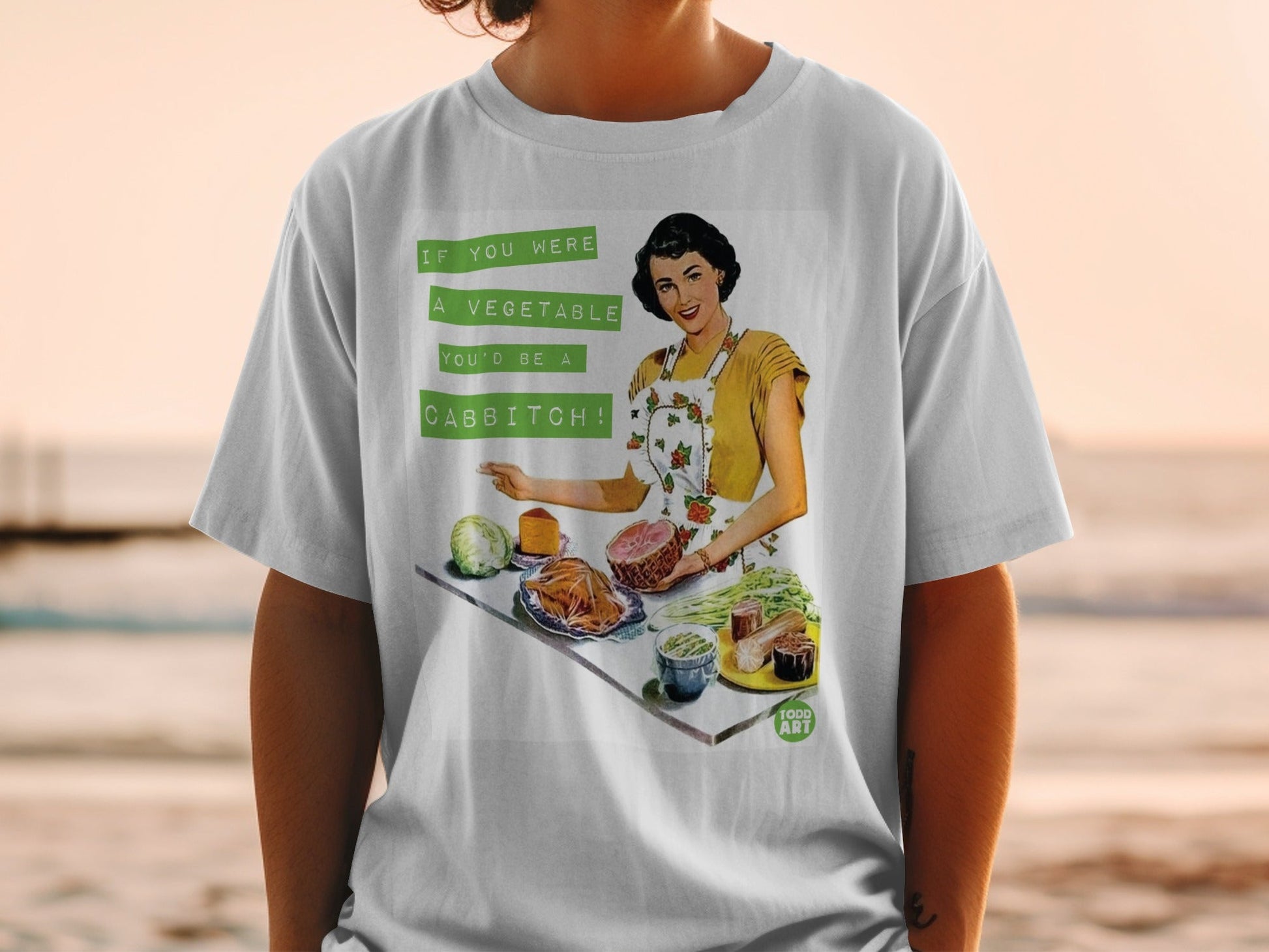 T-shirt with retro illustration of a woman holding ham, text "If you were a vegetable you'd be a cabbitch!"