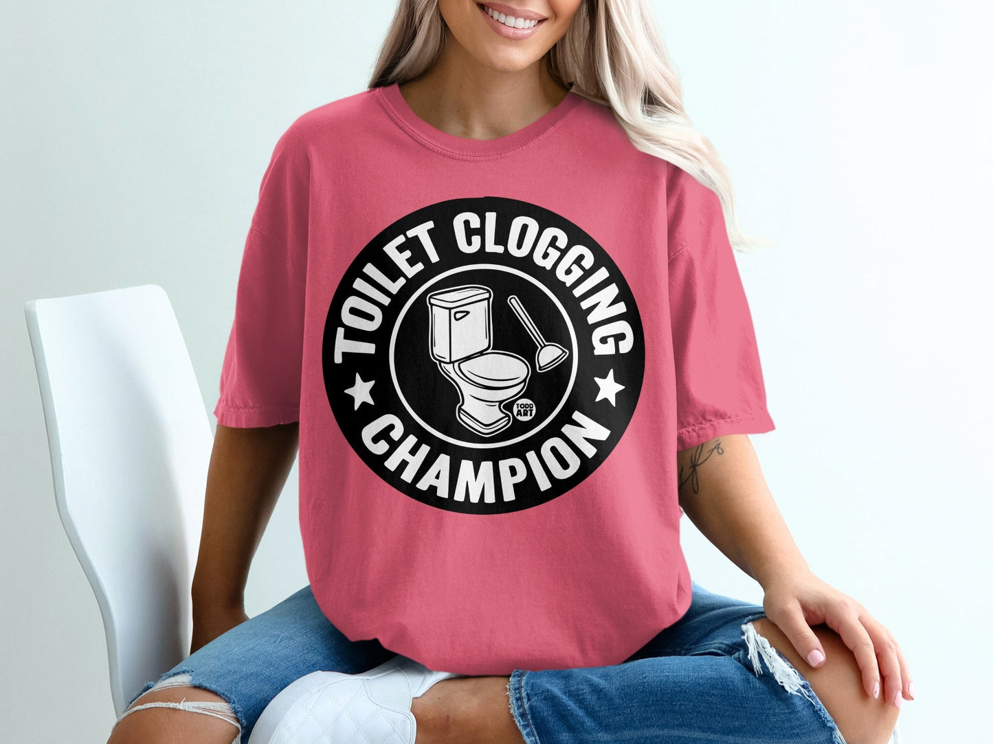 T-shirt with text "Toilet Clogging Champion" and toilet brush graphic.