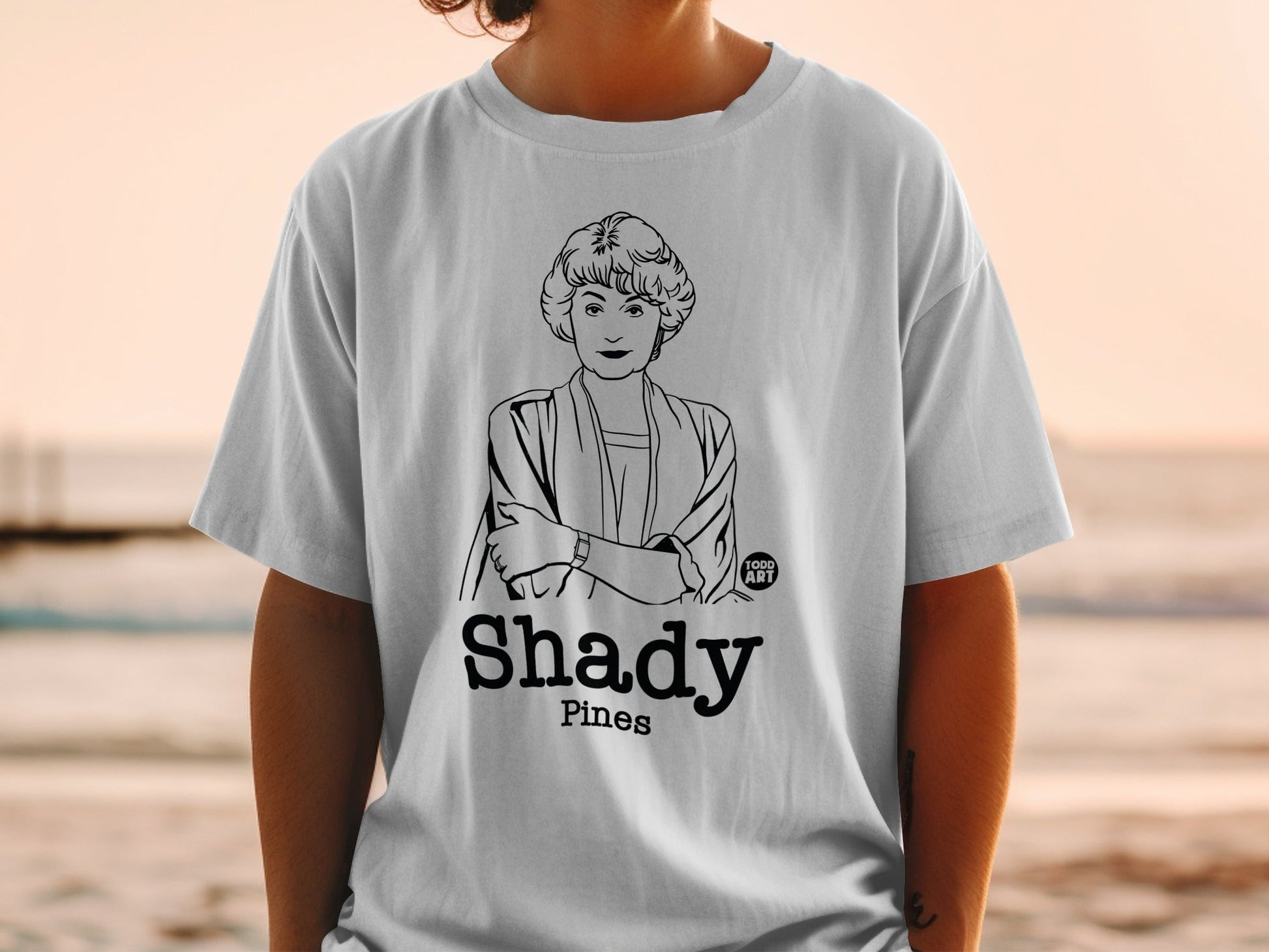 White t-shirt with cartoon portrait and "Shady Pines" text.