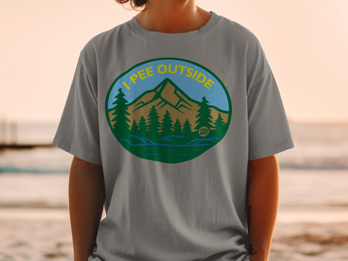 Circular badge with "I pee outside" text over a mountain and forest landscape.