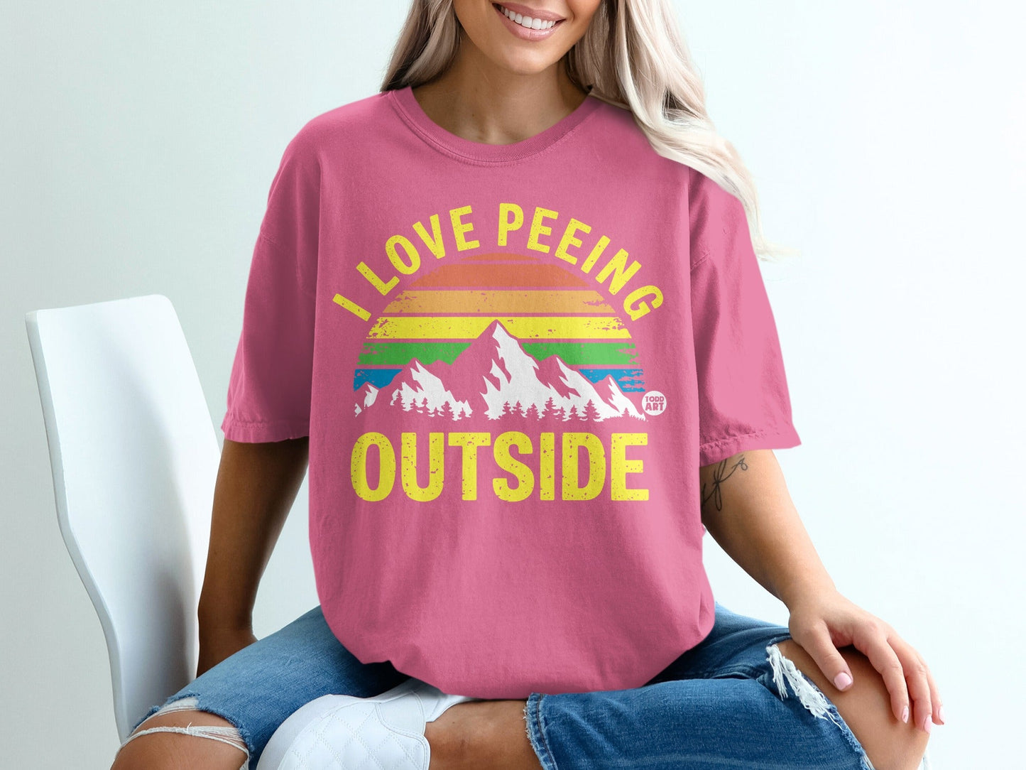 Pink t-shirt with "I LOVE PE**ING OUTSIDE" text and mountain graphic.