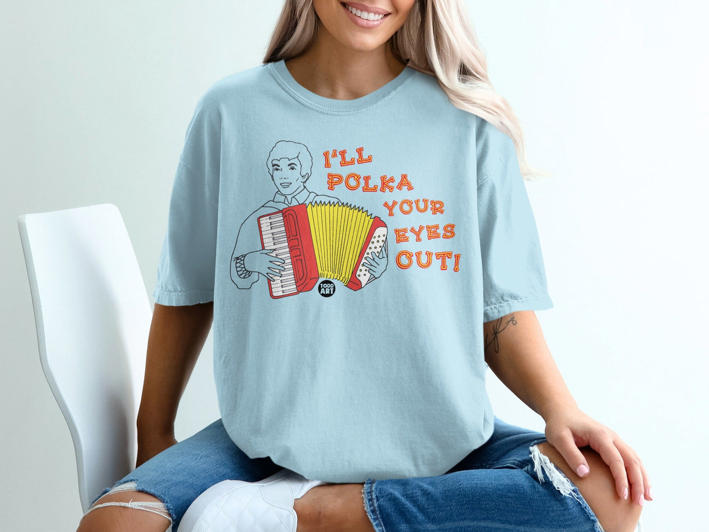 Light blue t-shirt with cartoon man playing accordion, text "I'll Polka Your Eyes Out!".