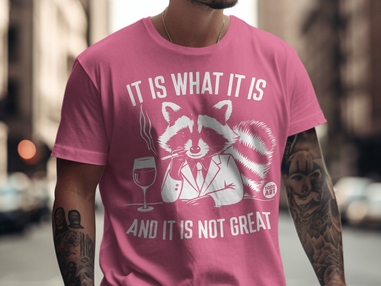 Raccoon in suit smoking, with wine glass, on pink t-shirt.
