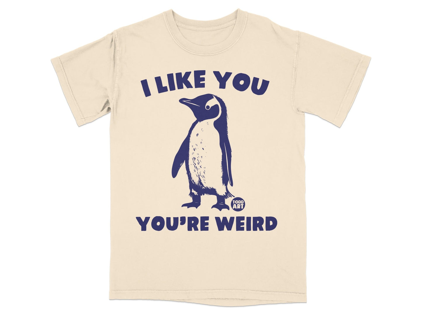 Cream t-shirt with a navy blue penguin and "I like you you're weird" text.