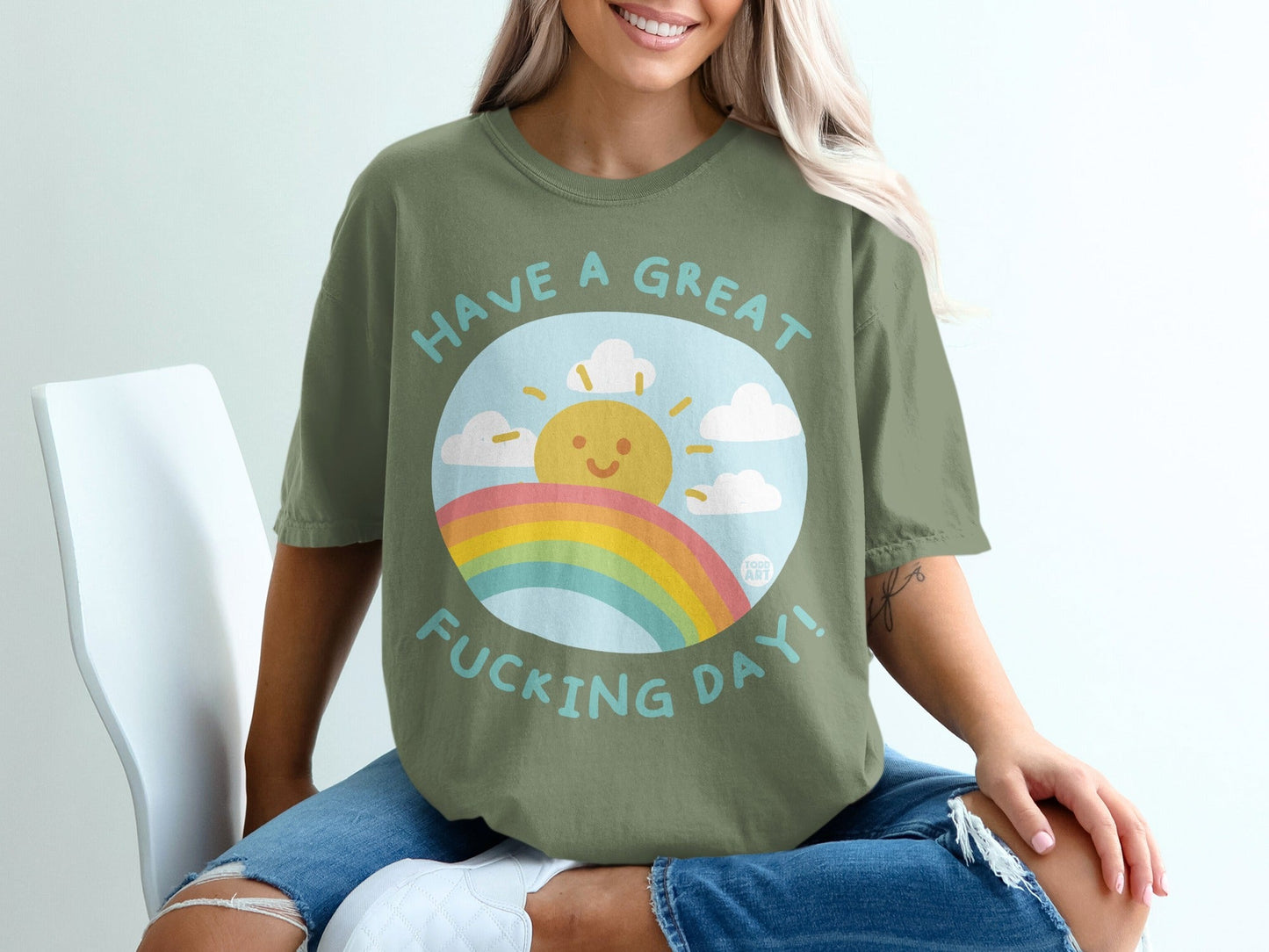 Green t-shirt with sun, rainbow, and "Have a great fucking day!" text.