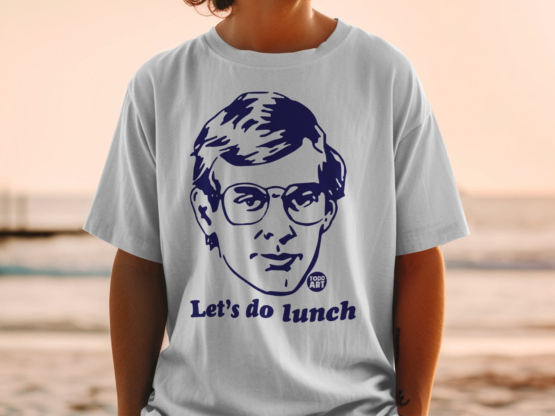 White t-shirt with navy blue graphic of a man's face and "Let's do lunch".