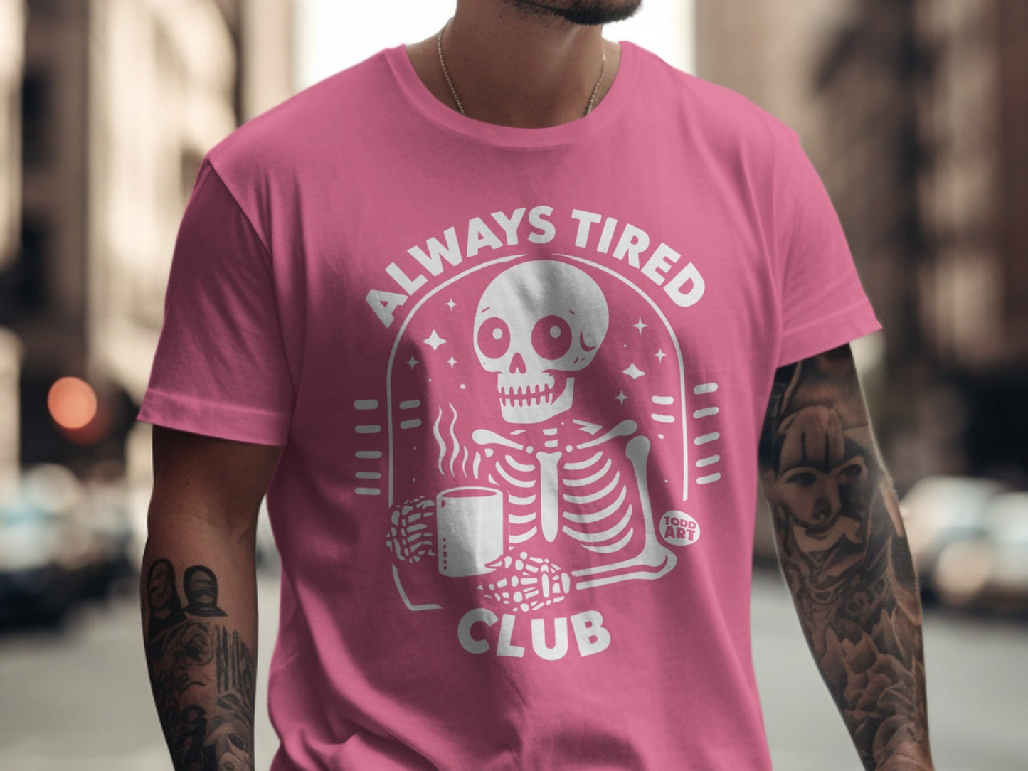 Pink t-shirt with white "Always Tired Club" text and skeleton graphic.