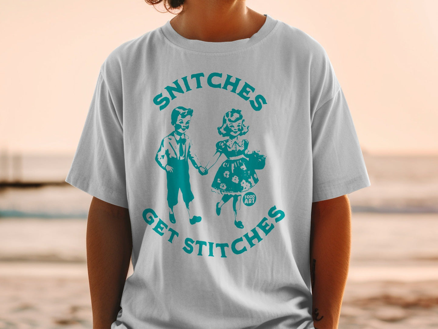 T-shirt with "Snitches Get Stitches" text and a vintage illustration of two children.